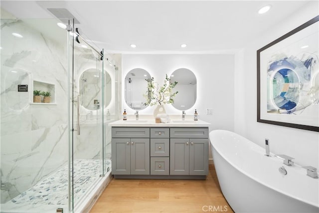 bathroom with hardwood / wood-style flooring, vanity, and plus walk in shower