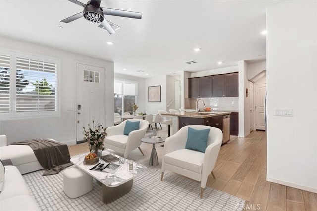 living room featuring ceiling fan, sink, and light wood-type flooring