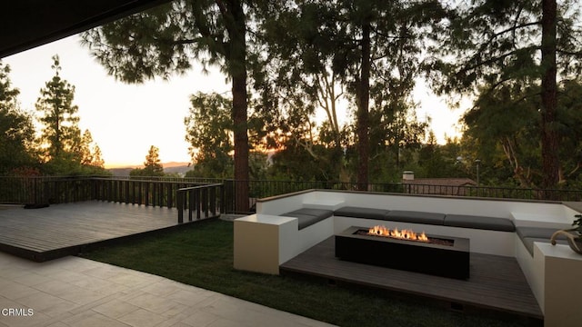 patio terrace at dusk featuring a deck and a fire pit