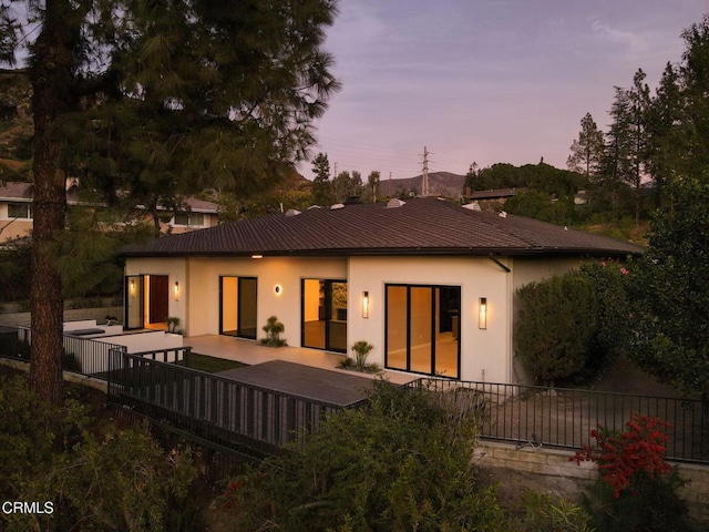 back house at dusk featuring a patio