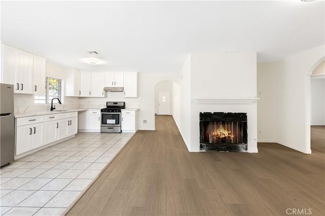 kitchen with appliances with stainless steel finishes, light hardwood / wood-style flooring, white cabinetry, and sink