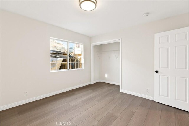 unfurnished bedroom with a closet and light wood-type flooring