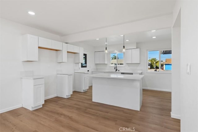 kitchen with sink, pendant lighting, a center island, light hardwood / wood-style floors, and white cabinetry