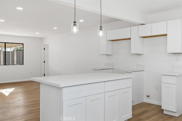 kitchen featuring white cabinets, hanging light fixtures, and light wood-type flooring