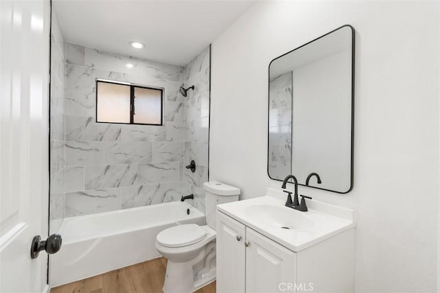 full bathroom featuring hardwood / wood-style floors, vanity, toilet, and tiled shower / bath combo