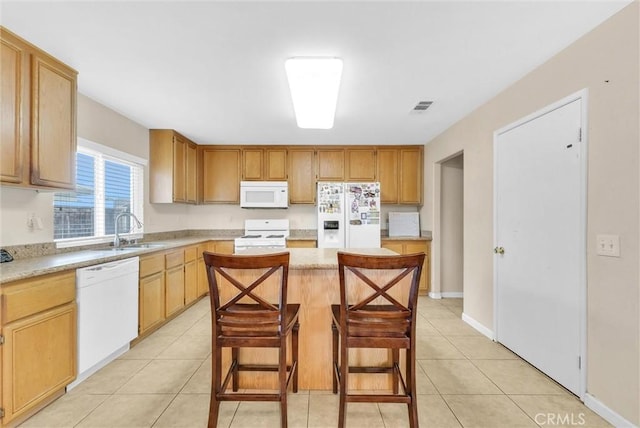 kitchen featuring a center island, a kitchen bar, white appliances, and light tile patterned flooring