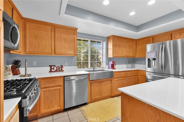 kitchen featuring a tray ceiling, sink, light tile patterned floors, and appliances with stainless steel finishes