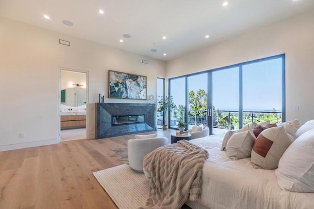 bedroom with a high end fireplace, ensuite bathroom, and light hardwood / wood-style flooring