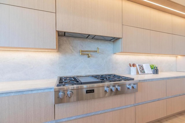 kitchen featuring light brown cabinets, stainless steel gas stovetop, ventilation hood, and tasteful backsplash