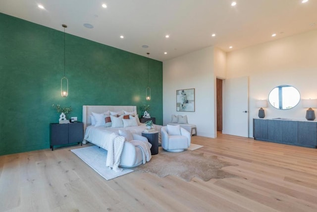 bedroom featuring light wood-type flooring and a high ceiling