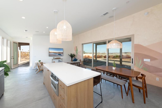 kitchen featuring decorative light fixtures, a healthy amount of sunlight, a kitchen island, and light brown cabinetry