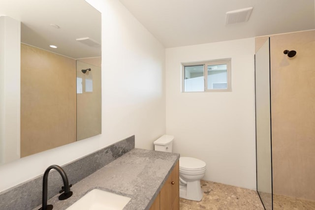 bathroom with vanity, toilet, and tiled shower