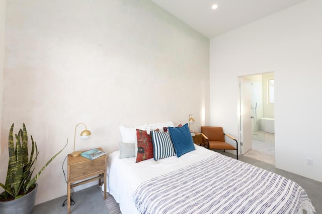 bedroom featuring ensuite bathroom and high vaulted ceiling