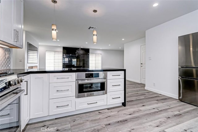 kitchen featuring white cabinetry, hanging light fixtures, backsplash, appliances with stainless steel finishes, and light wood-type flooring