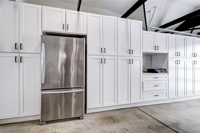 kitchen featuring stainless steel fridge, white cabinetry, and backsplash