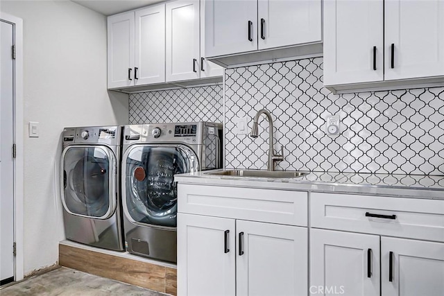 clothes washing area with cabinets, sink, and washing machine and clothes dryer