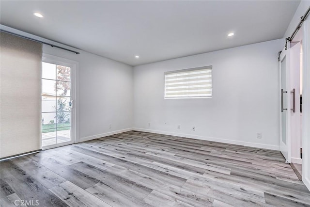 empty room with a barn door and light hardwood / wood-style flooring