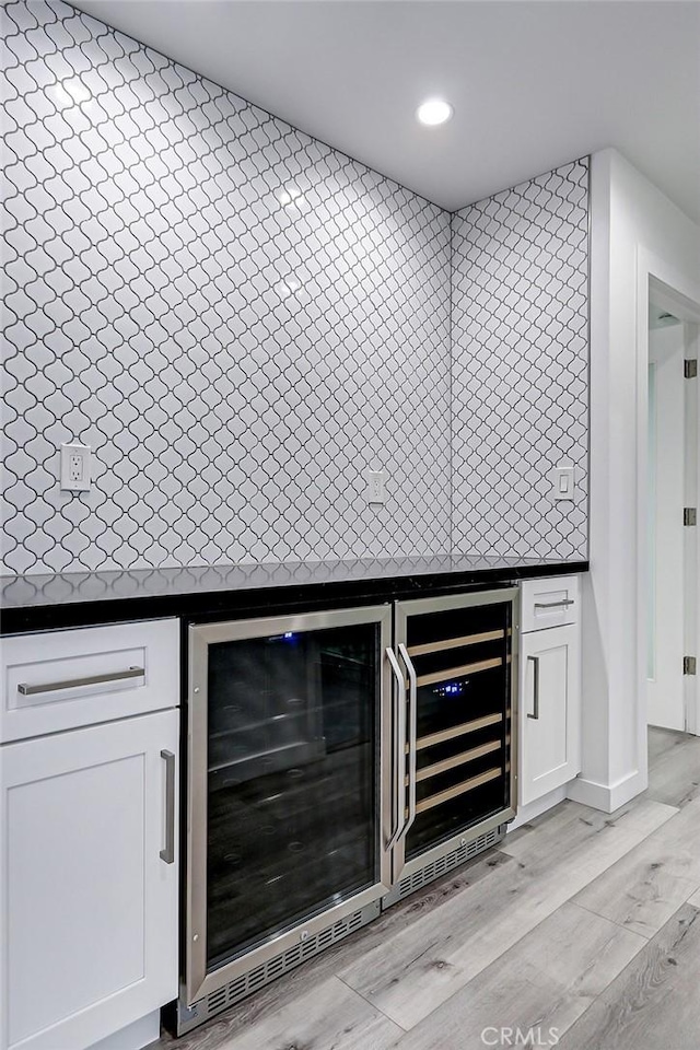 bar featuring wine cooler, light wood-type flooring, and white cabinetry