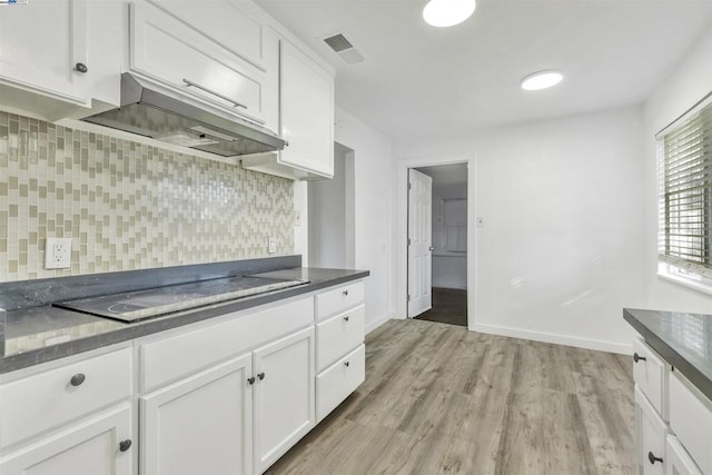 kitchen with decorative backsplash, light wood-type flooring, white cabinetry, and electric stovetop