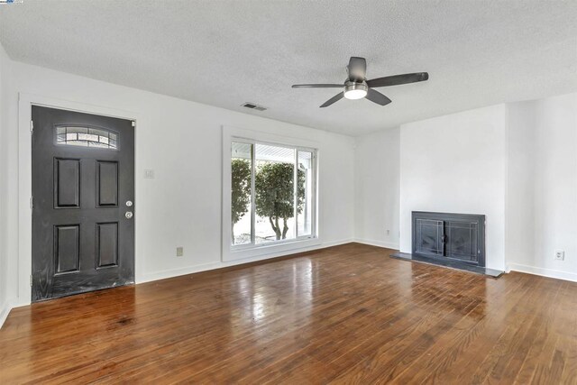 unfurnished living room featuring a textured ceiling, dark hardwood / wood-style flooring, and ceiling fan