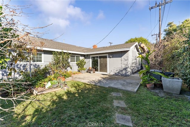 rear view of house featuring a lawn, stucco siding, and a patio area
