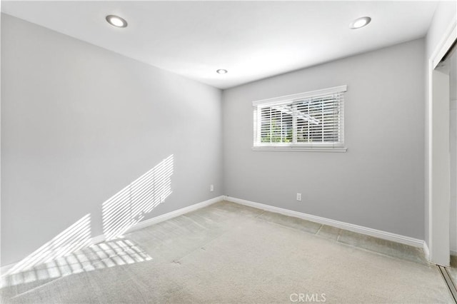 empty room featuring baseboards, light colored carpet, and recessed lighting