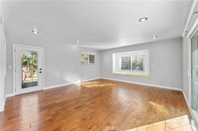 empty room featuring baseboards, recessed lighting, and wood-type flooring