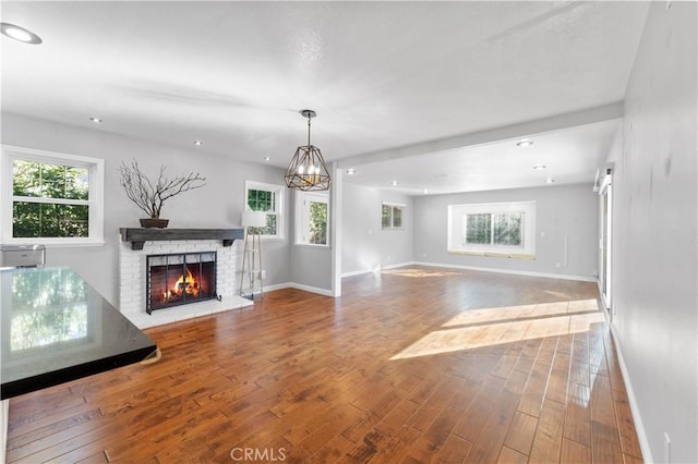 unfurnished living room with baseboards, a fireplace, a wealth of natural light, and hardwood / wood-style flooring
