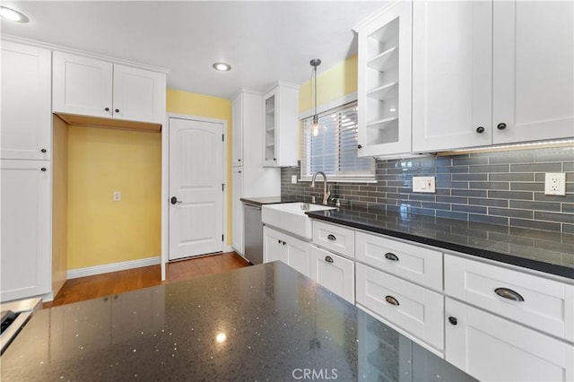 kitchen with dishwasher, glass insert cabinets, white cabinetry, a sink, and backsplash