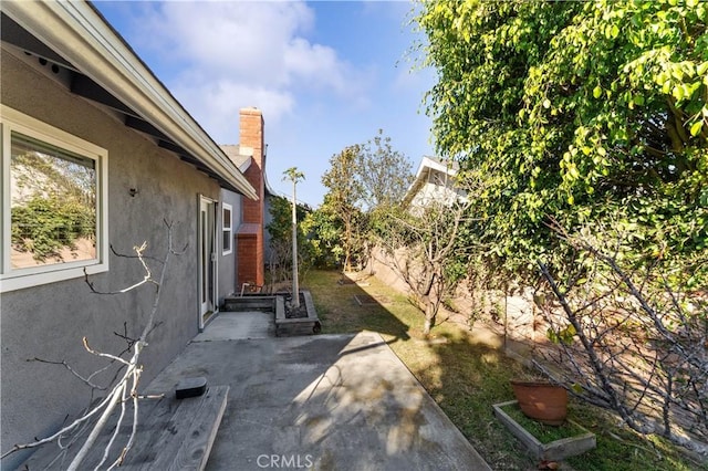 exterior space featuring a fenced backyard, a chimney, stucco siding, and a patio area