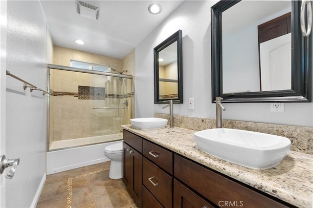 full bathroom with toilet, a sink, double vanity, and visible vents