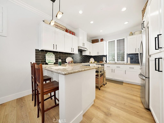 kitchen featuring white cabinets, decorative light fixtures, light hardwood / wood-style flooring, and crown molding