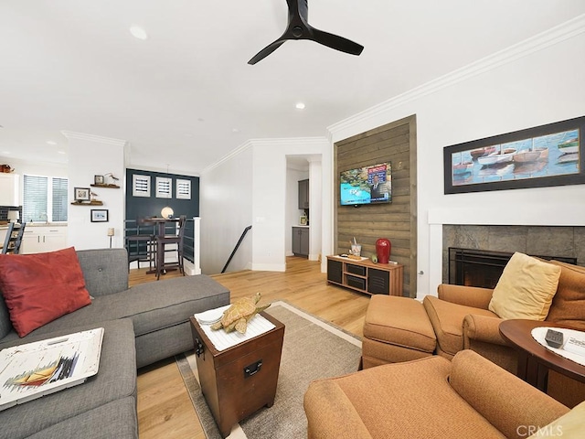 living room with ceiling fan, crown molding, and light hardwood / wood-style flooring