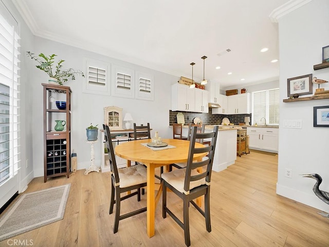 dining space with ornamental molding, a wealth of natural light, and light hardwood / wood-style flooring