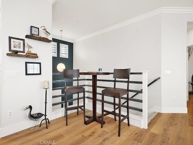 dining room with light hardwood / wood-style flooring and crown molding