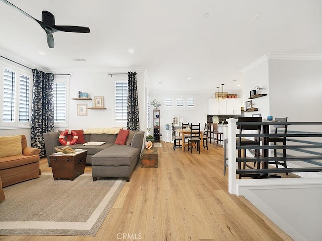 living room with ceiling fan, ornamental molding, and light hardwood / wood-style flooring