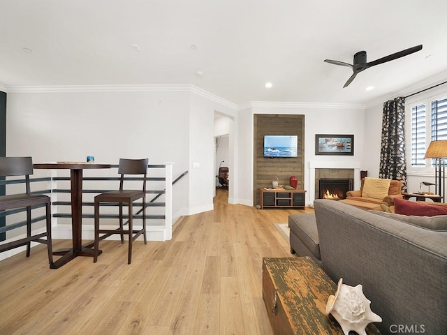 living room with ceiling fan, a fireplace, light hardwood / wood-style floors, and ornamental molding