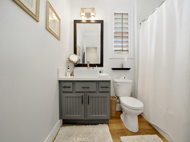 bathroom featuring crown molding, vanity, wood-type flooring, and toilet