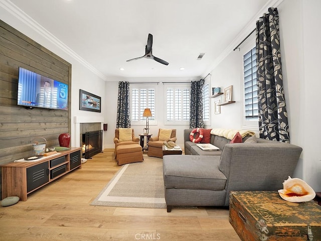 living room with wooden walls, light hardwood / wood-style flooring, crown molding, and a healthy amount of sunlight