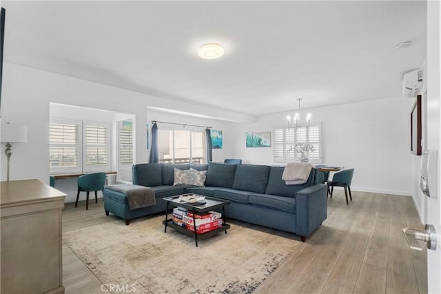 living room featuring a chandelier, light hardwood / wood-style flooring, an AC wall unit, and a healthy amount of sunlight