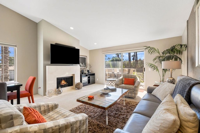 carpeted living room with a high end fireplace, a healthy amount of sunlight, and vaulted ceiling