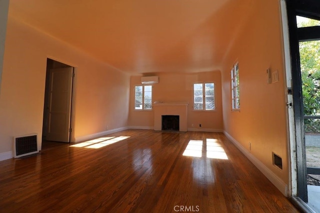 unfurnished living room with an AC wall unit and hardwood / wood-style floors