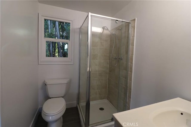 bathroom featuring toilet, a shower with shower door, and vanity