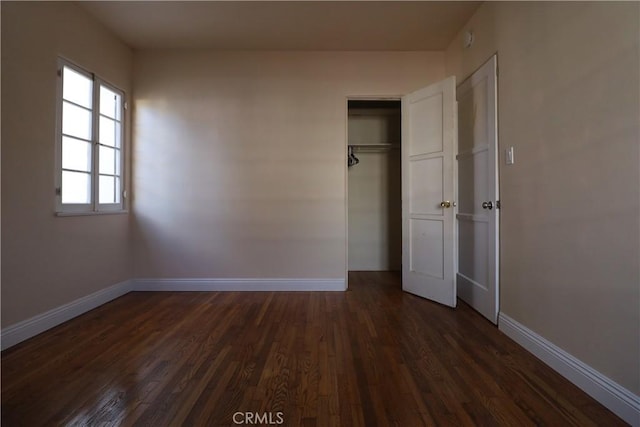 unfurnished bedroom with dark wood-type flooring and a closet