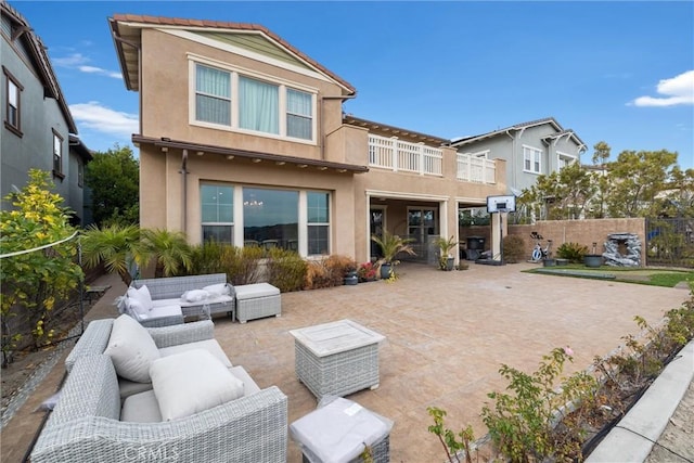 rear view of property featuring outdoor lounge area, a balcony, and a patio