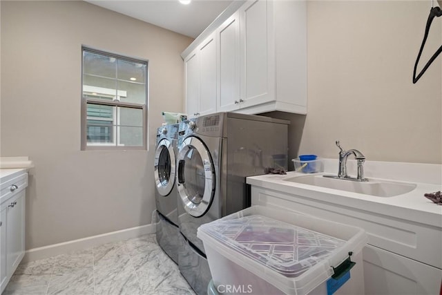 clothes washing area featuring washer and dryer, sink, and cabinets