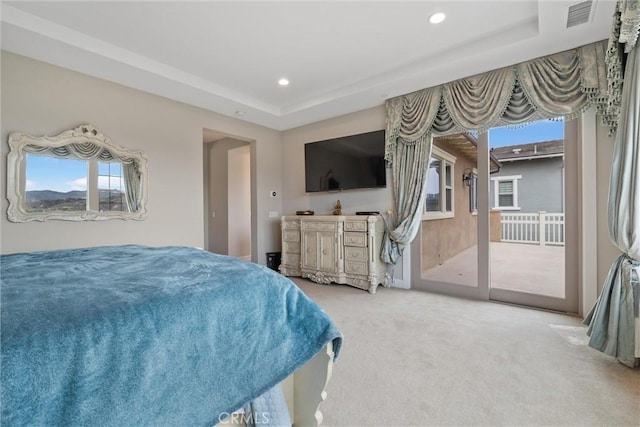 carpeted bedroom with access to outside and a raised ceiling