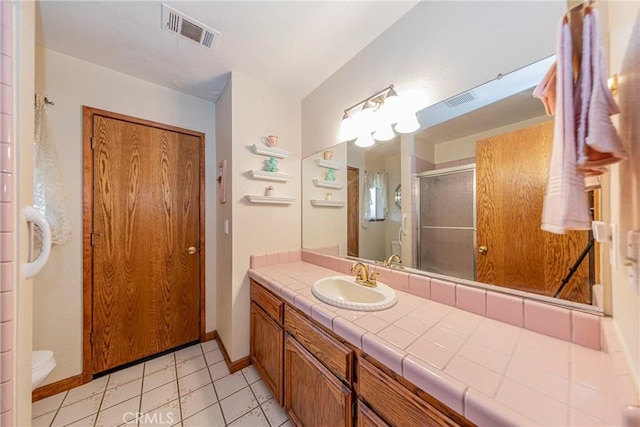 bathroom with tile patterned flooring, vanity, toilet, and a shower with shower door