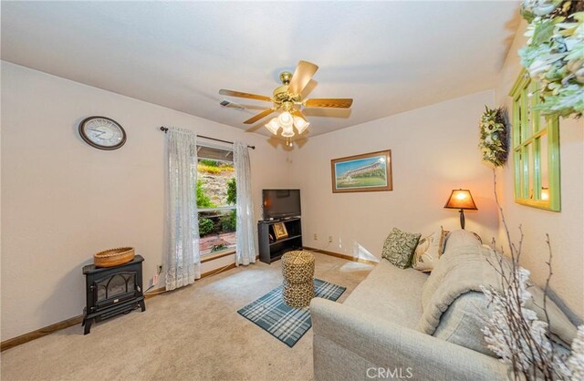 living room featuring a wood stove, light carpet, and ceiling fan