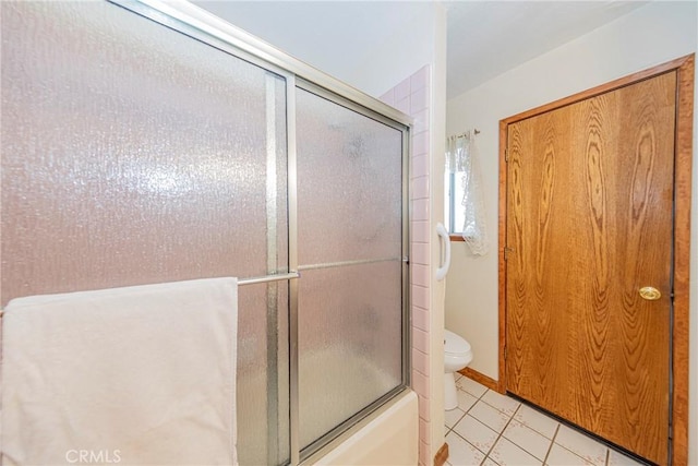 bathroom featuring tile patterned floors, toilet, and enclosed tub / shower combo